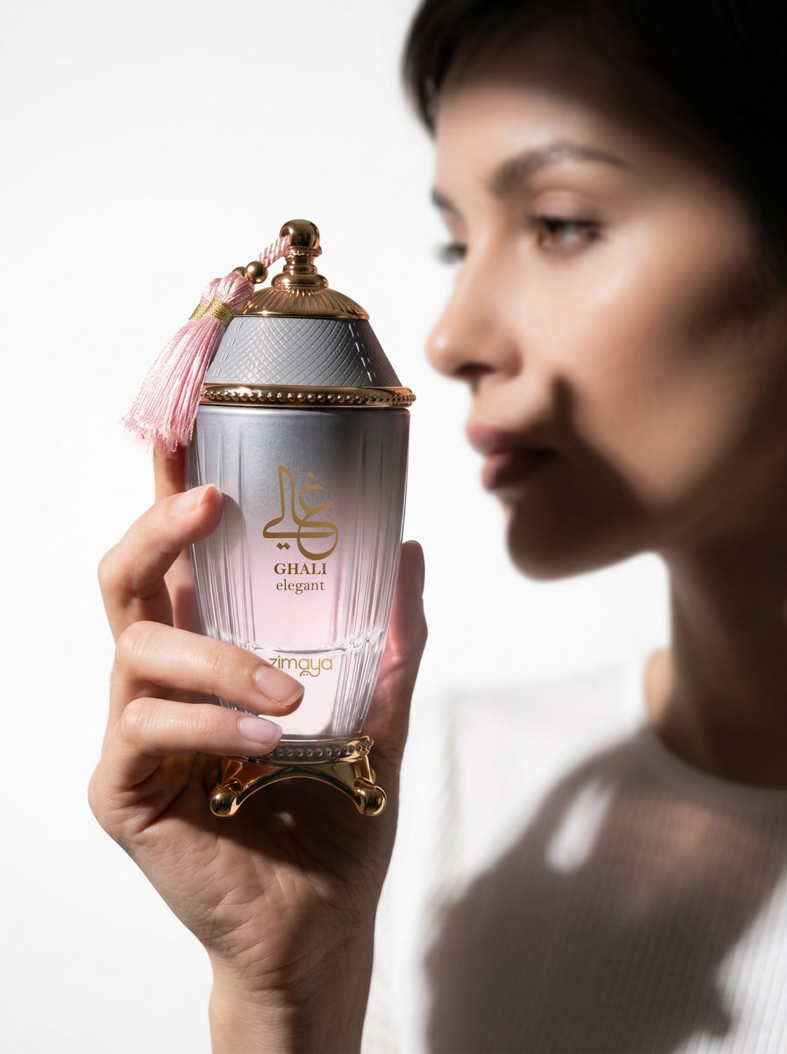 A woman holding Ghali Elegant perfume near her face in soft natural light — AI perfume imagery by The Media Lab.