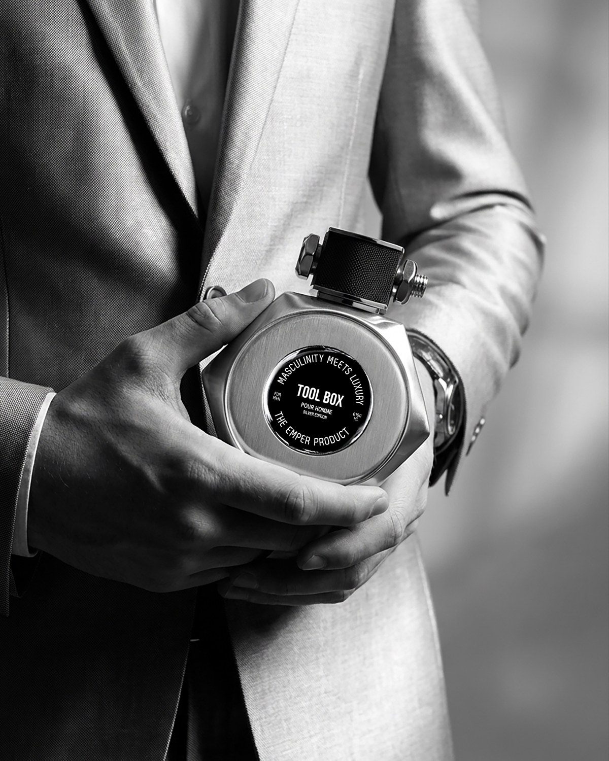 A person in a grey jacket holding an Emper Tool Box perfume bottle in monochrome — AI perfume imagery by The Media Lab.