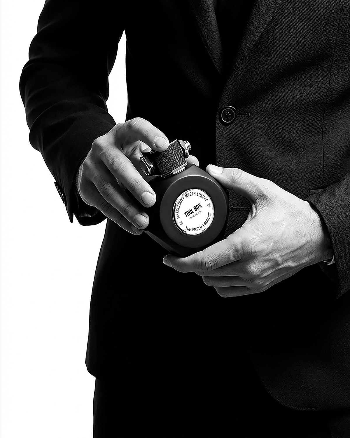 A person dressed in black holding an Emper Tool Box perfume bottle — AI perfume imagery by The Media Lab.
