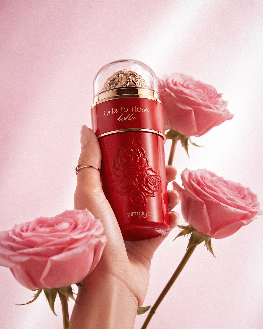 A hand holding red Ode to Rose perfume among pink roses — AI perfume imagery by The Media Lab.